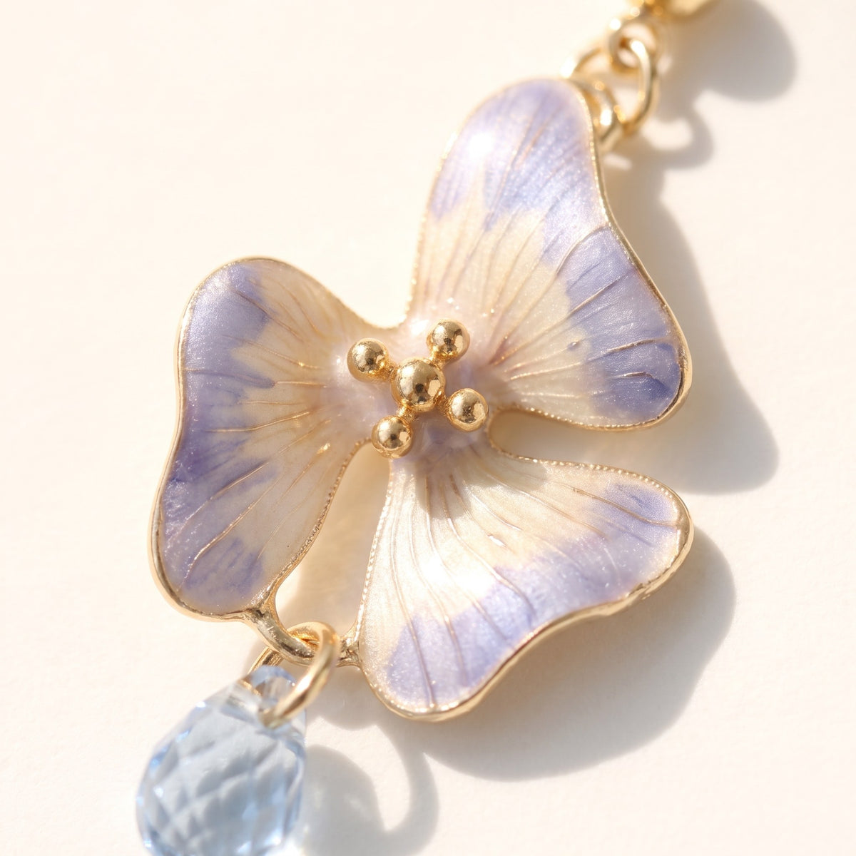 Close detail of the lilac enamel pansy and blue briolette