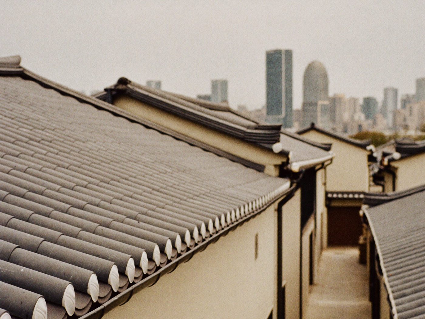 Hanok rooftops in Seoul, with the modern city hazy behind them