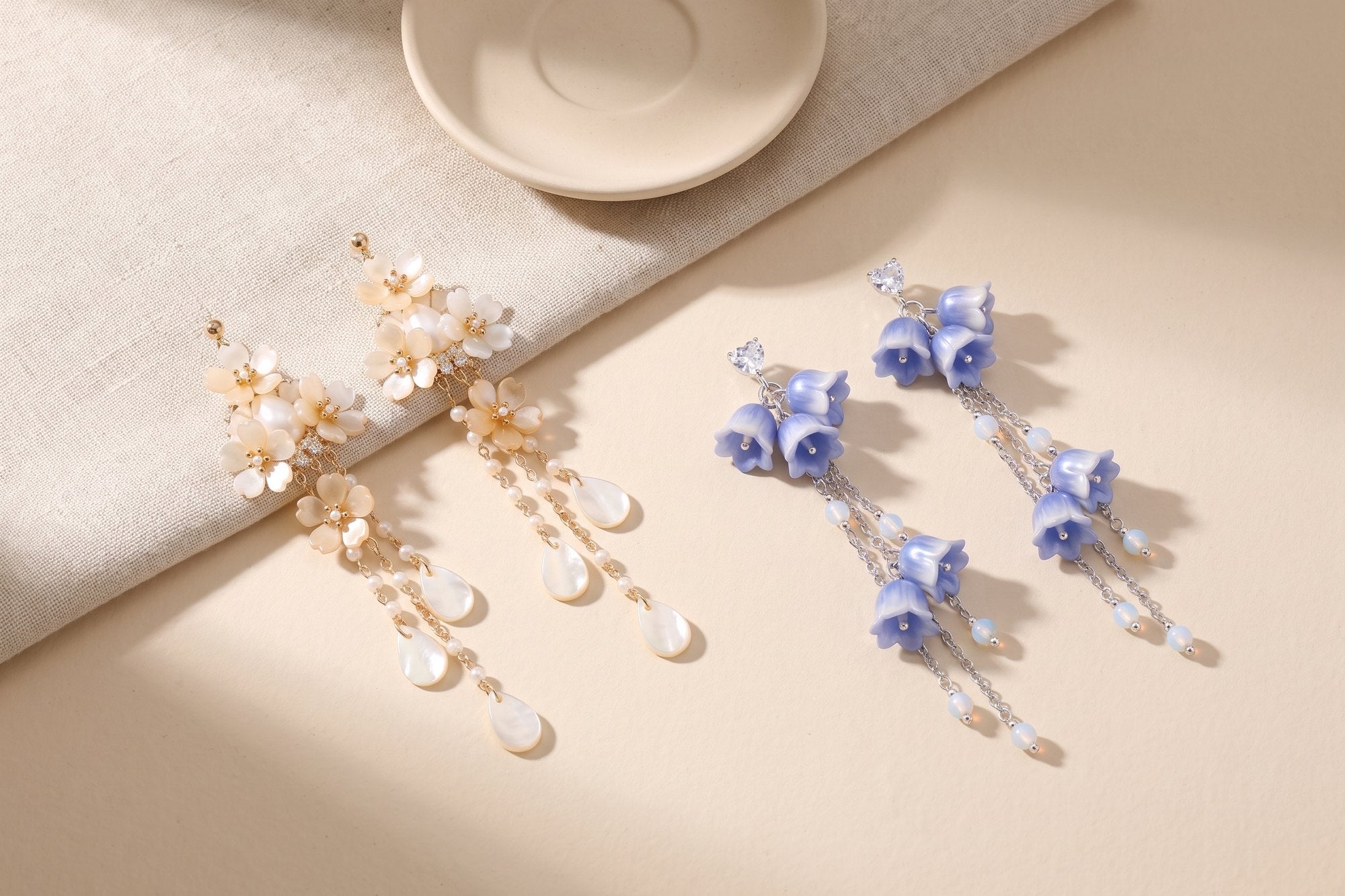 The Moonpetal and Bluebell earrings laid out on unbleached linen