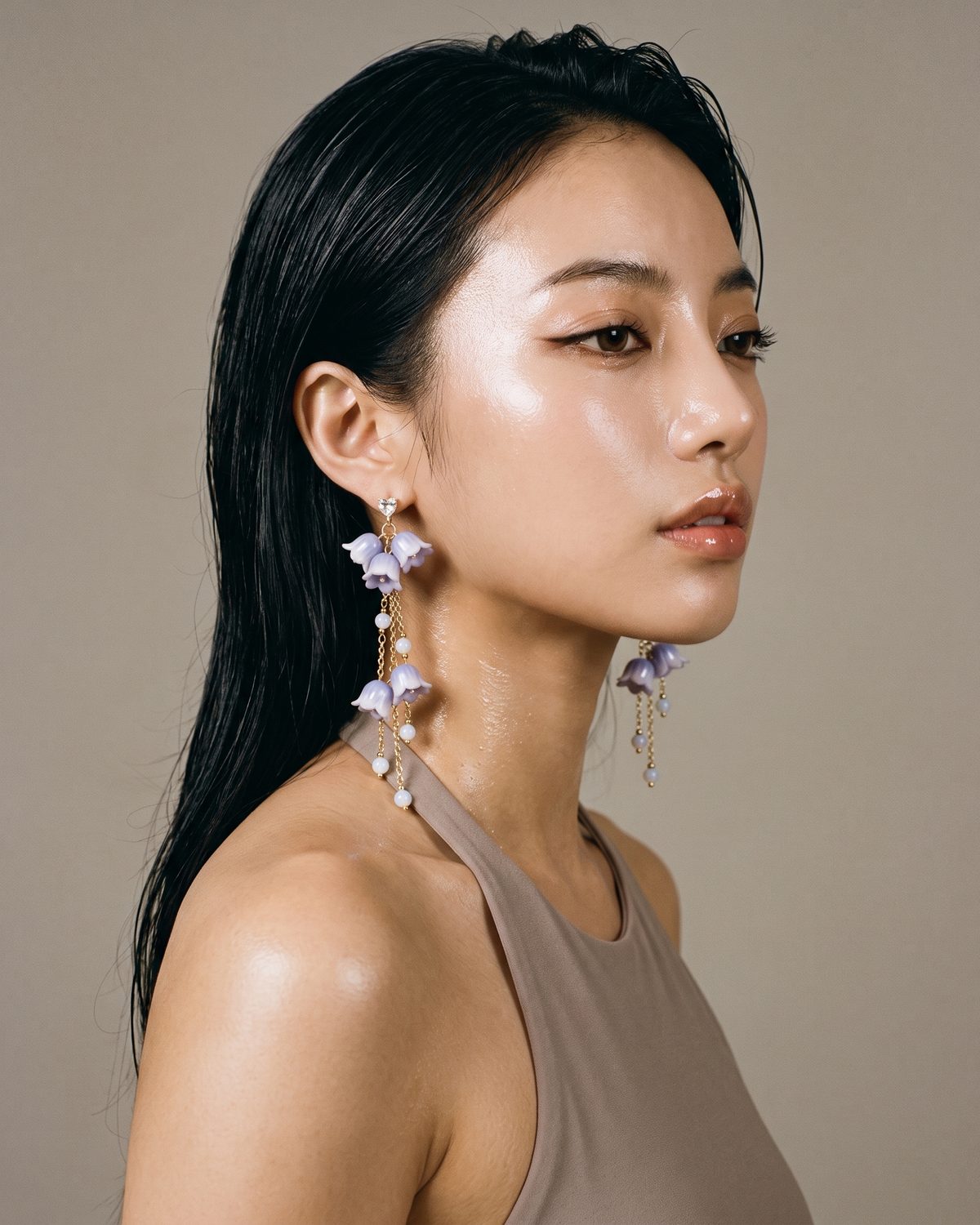 A model wearing a long gold drop earring, photographed close