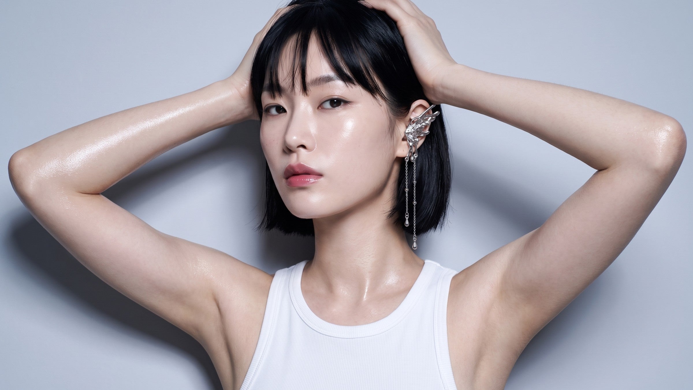 A model with both hands pushed up into her hair, wearing the Seraph ear cuff